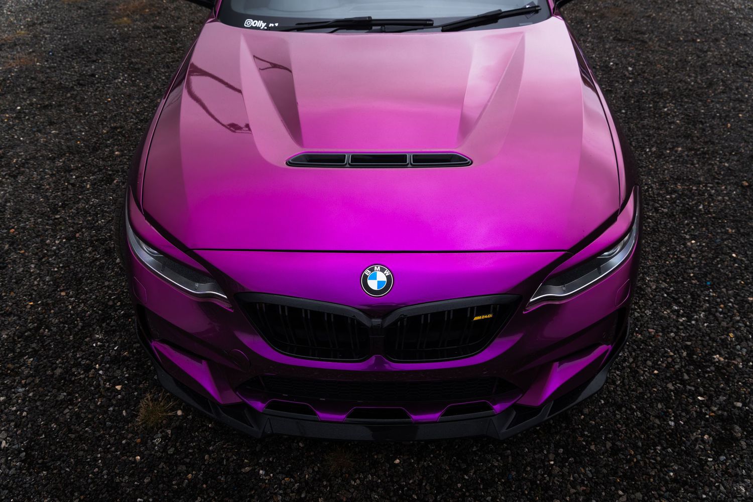 Top-down view of a pink BMW with aggressive wide body kit and hood vents.