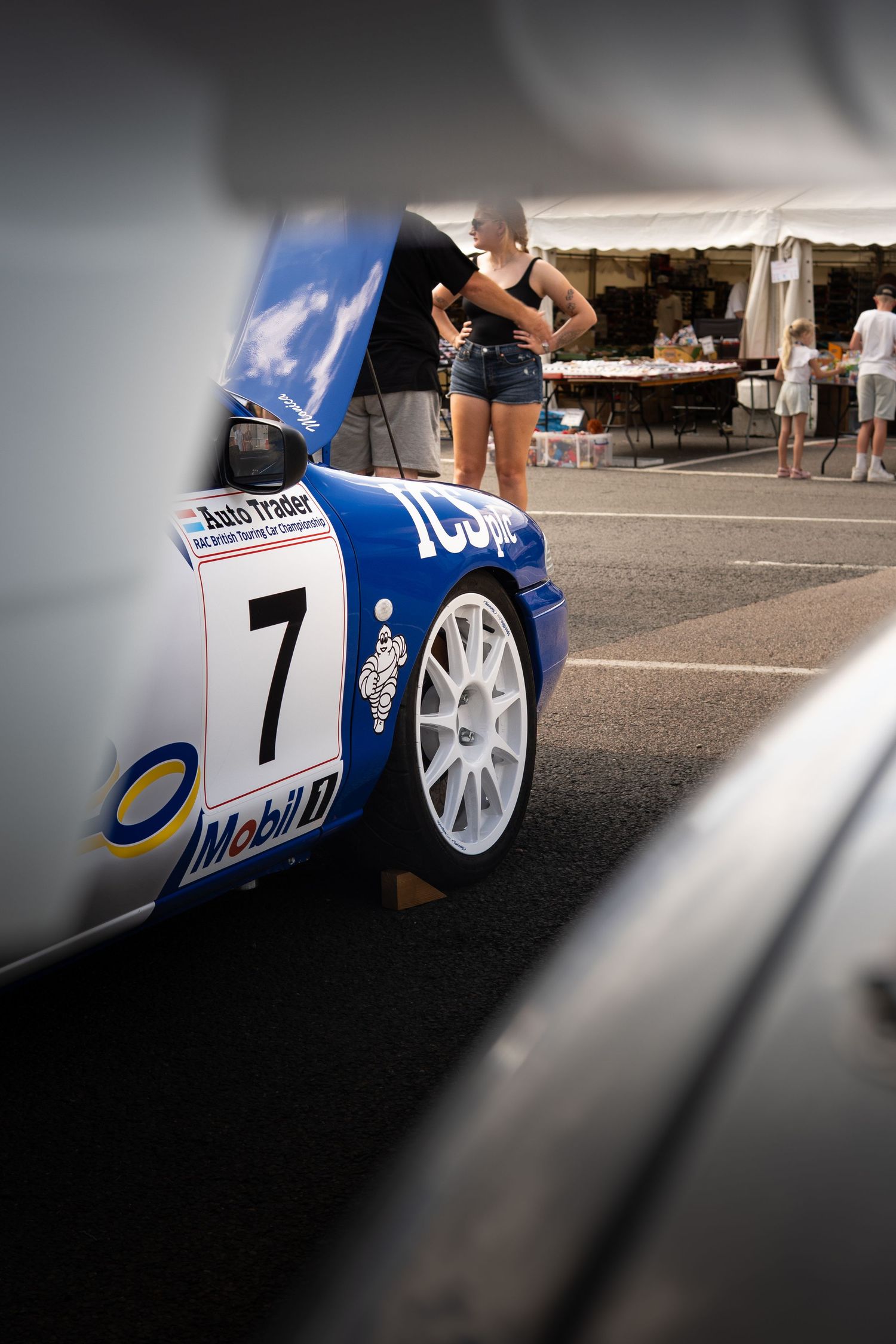 Blue AutoTrader number 7 Mobil race car with open hood at paddock event.