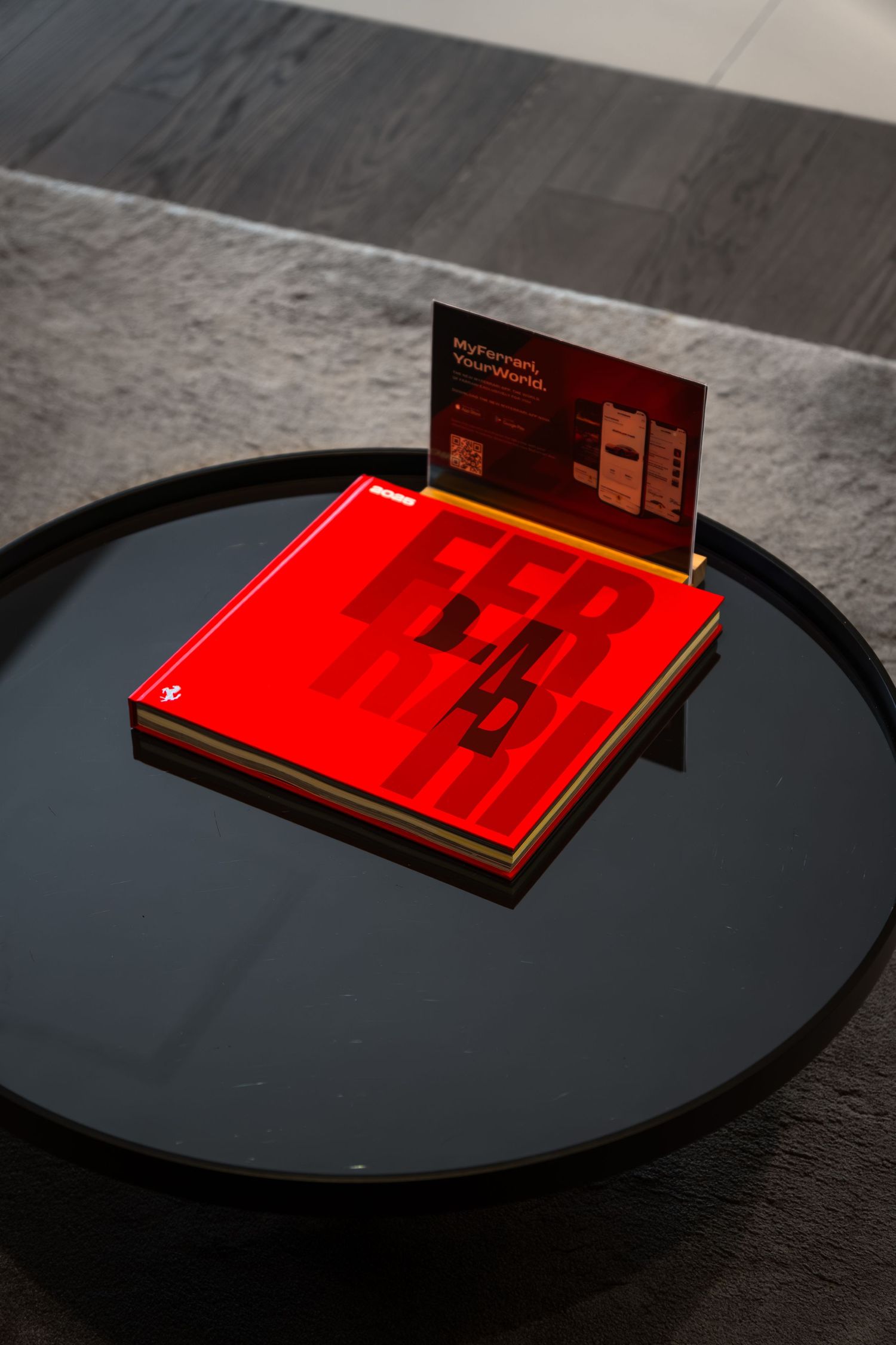 Red book with bold typography displayed on a black round coffee table with a dark marketing card stand.