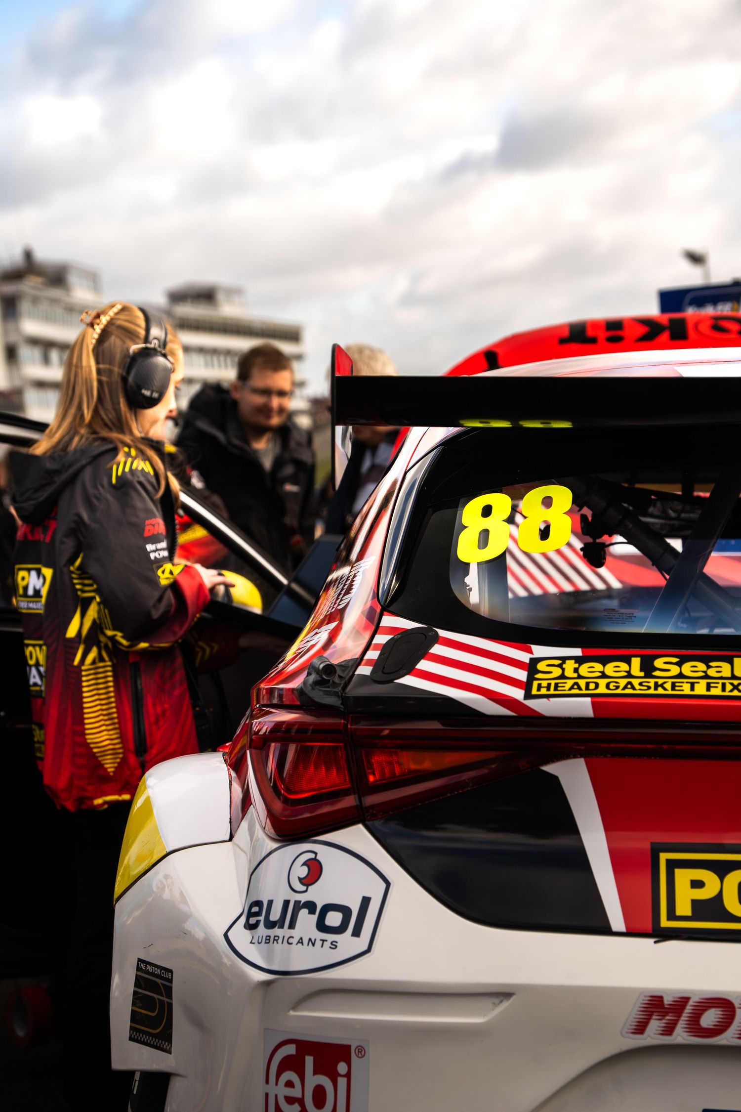 A race team member standing beside car number 88 with Eurol sponsorship in the paddock.