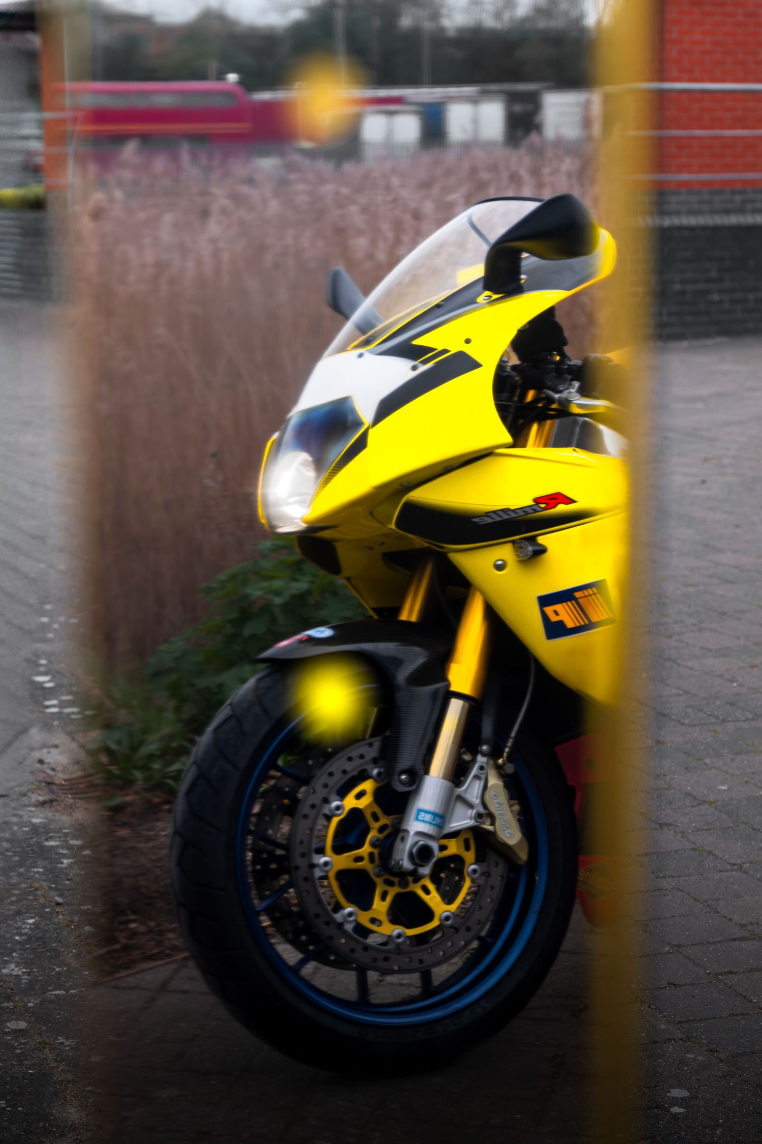 Close-up of yellow Aprilia RSV motorcycle front fairing with blue brake disc.