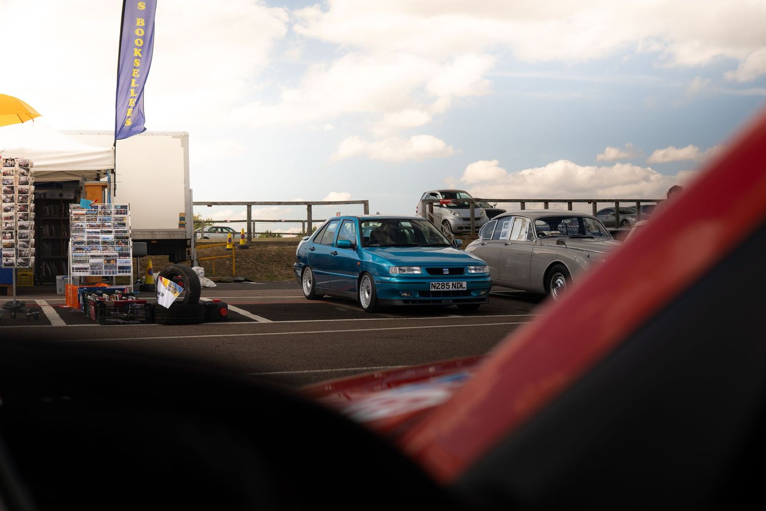 Teal Seat hatchback road car photographed from inside a red race car at circuit.