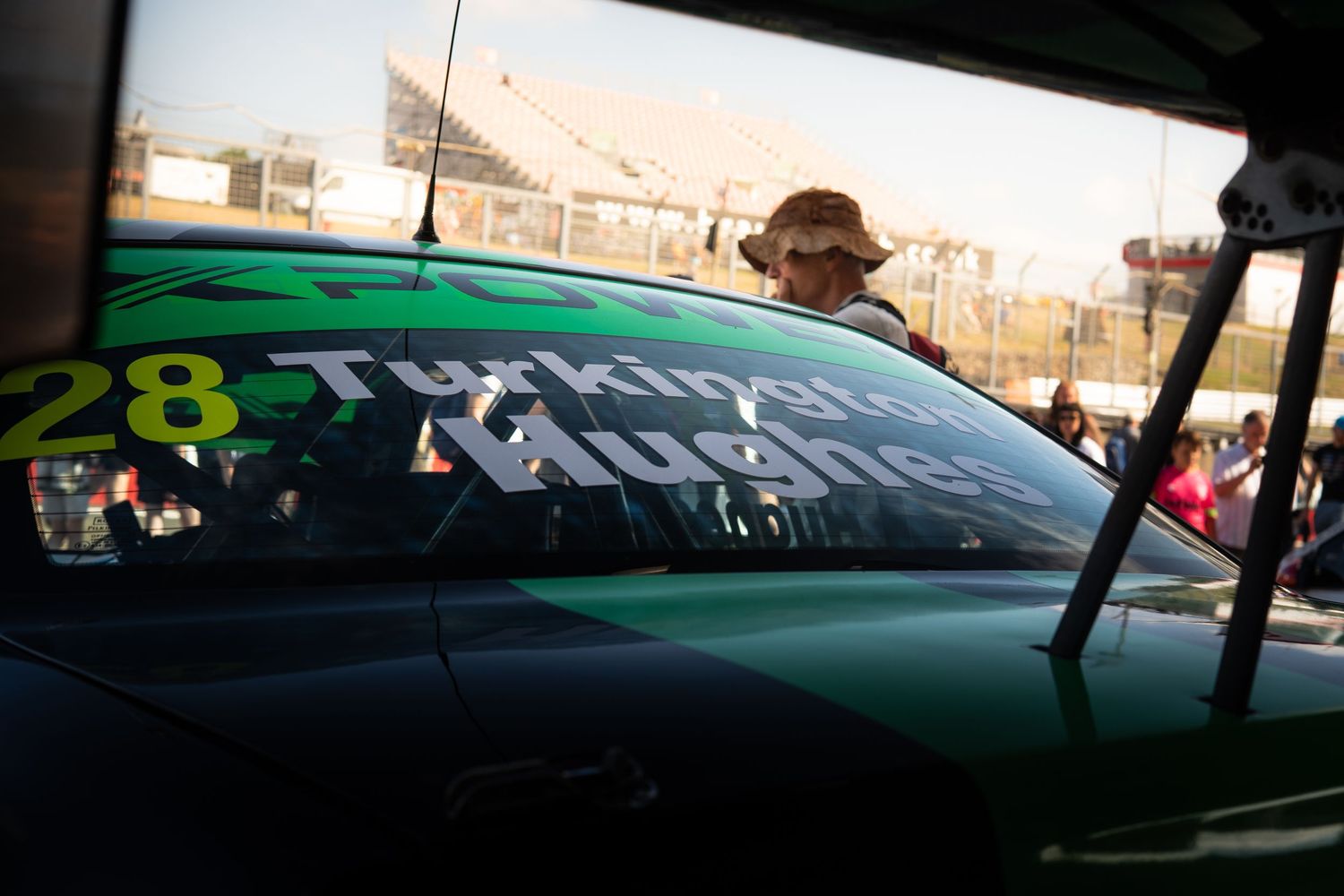 Close-up of a green racing car number 28 with a driver visible through the window.