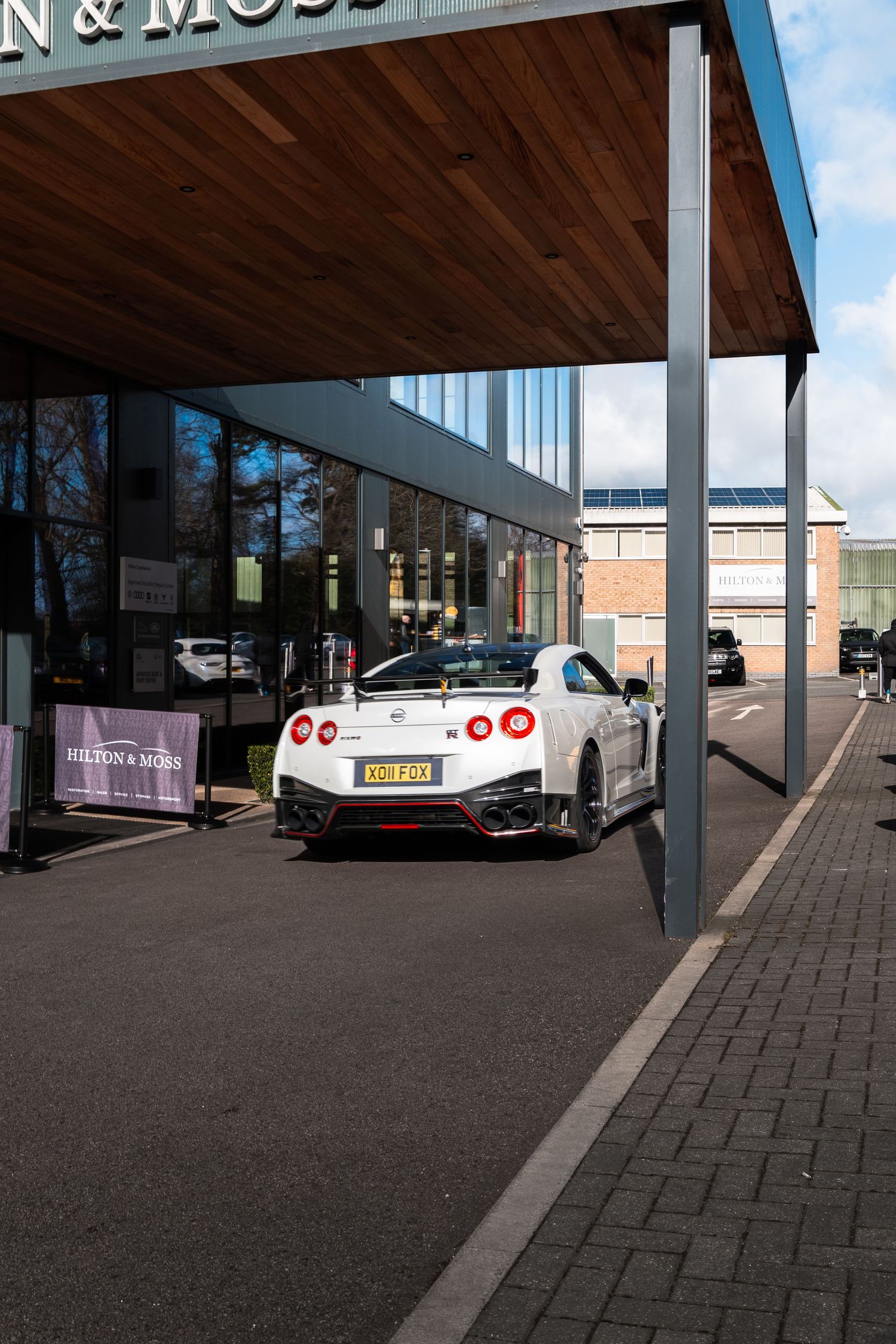 White Nissan GT-R Nismo with racing livery parked outside Hilton & Moss prestige car dealership.