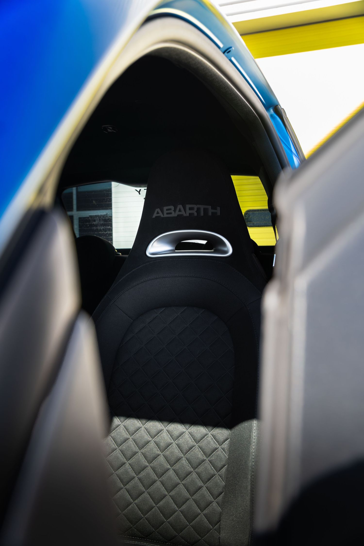 Close-up of Abarth quilted sport seats viewed through the open window of a blue Abarth 500.