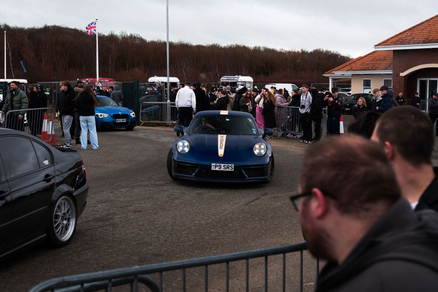 Dark blue Porsche 911 surrounded by crowds at a UK car show event.