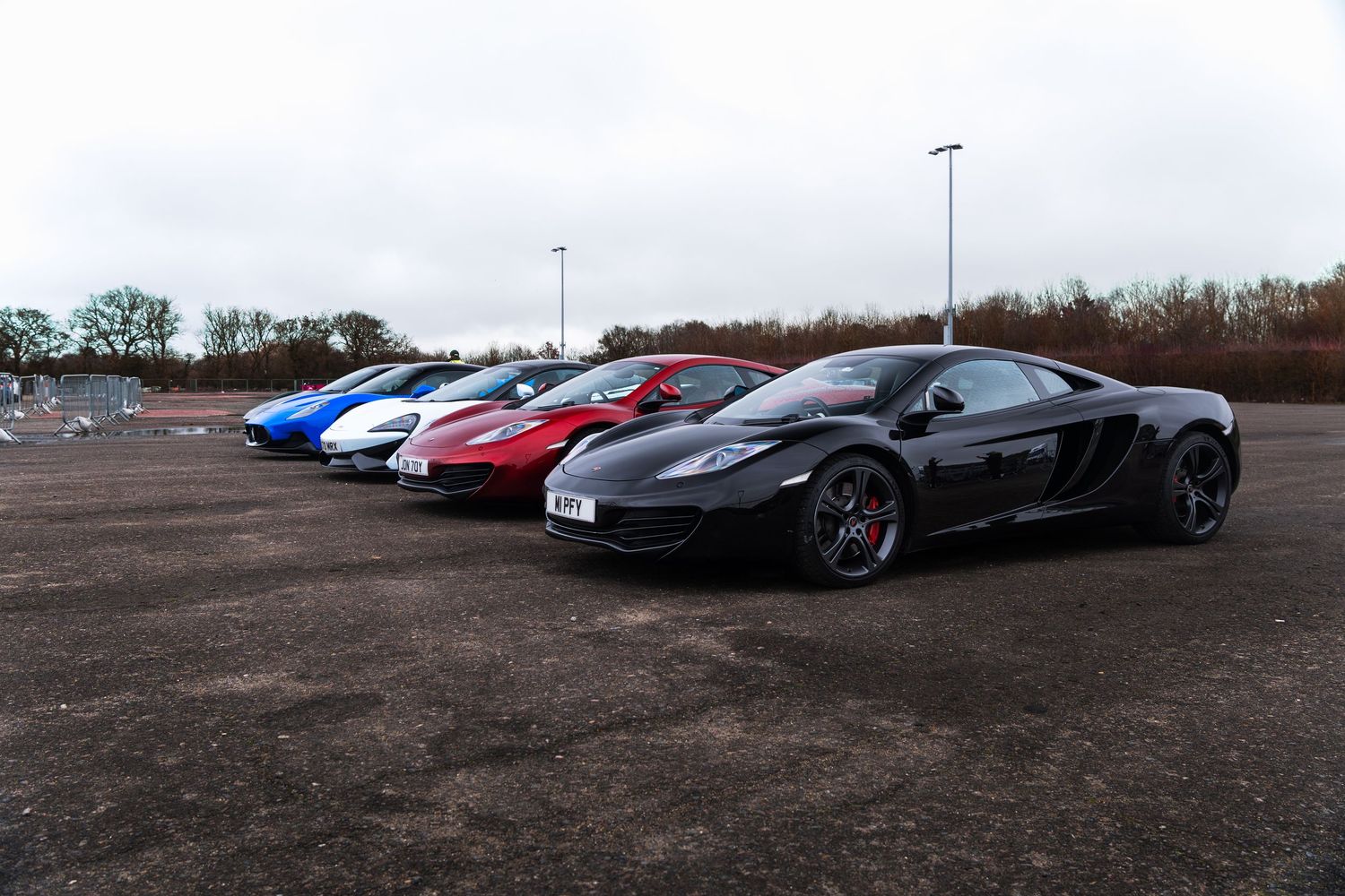 Row of colorful supercars including McLaren MP4-12C at a UK car meet.