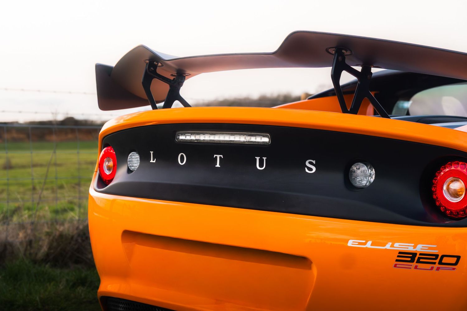 Rear view of orange Lotus Elise 360 Cup with large spoiler wing and LED brake lights.