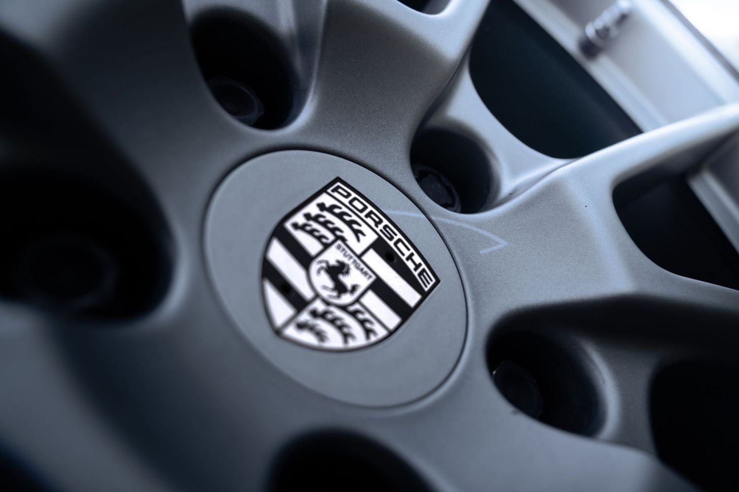 Close-up of Porsche crest center cap on dark alloy wheel of a Cayman GTS.