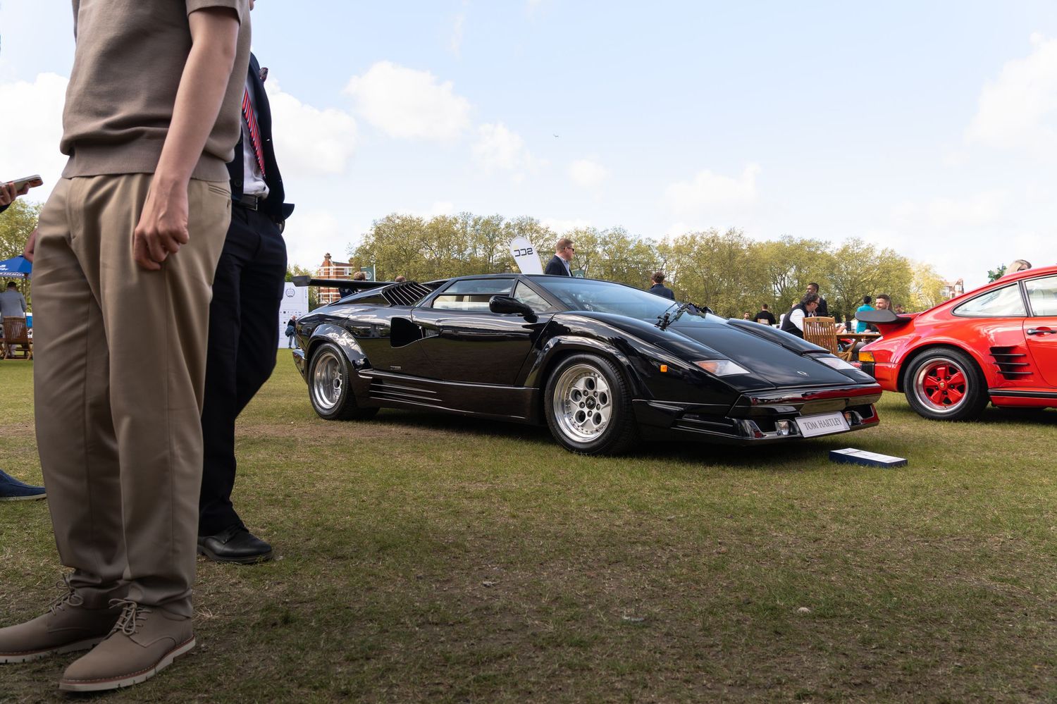 Classic black Lamborghini Countach on display at an outdoor luxury car show event.