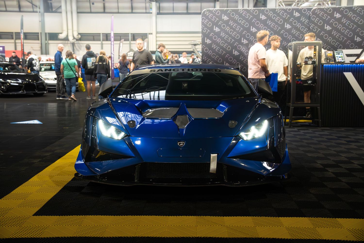 Front view of a blue Lamborghini Huracan with LED headlights at an auto show.