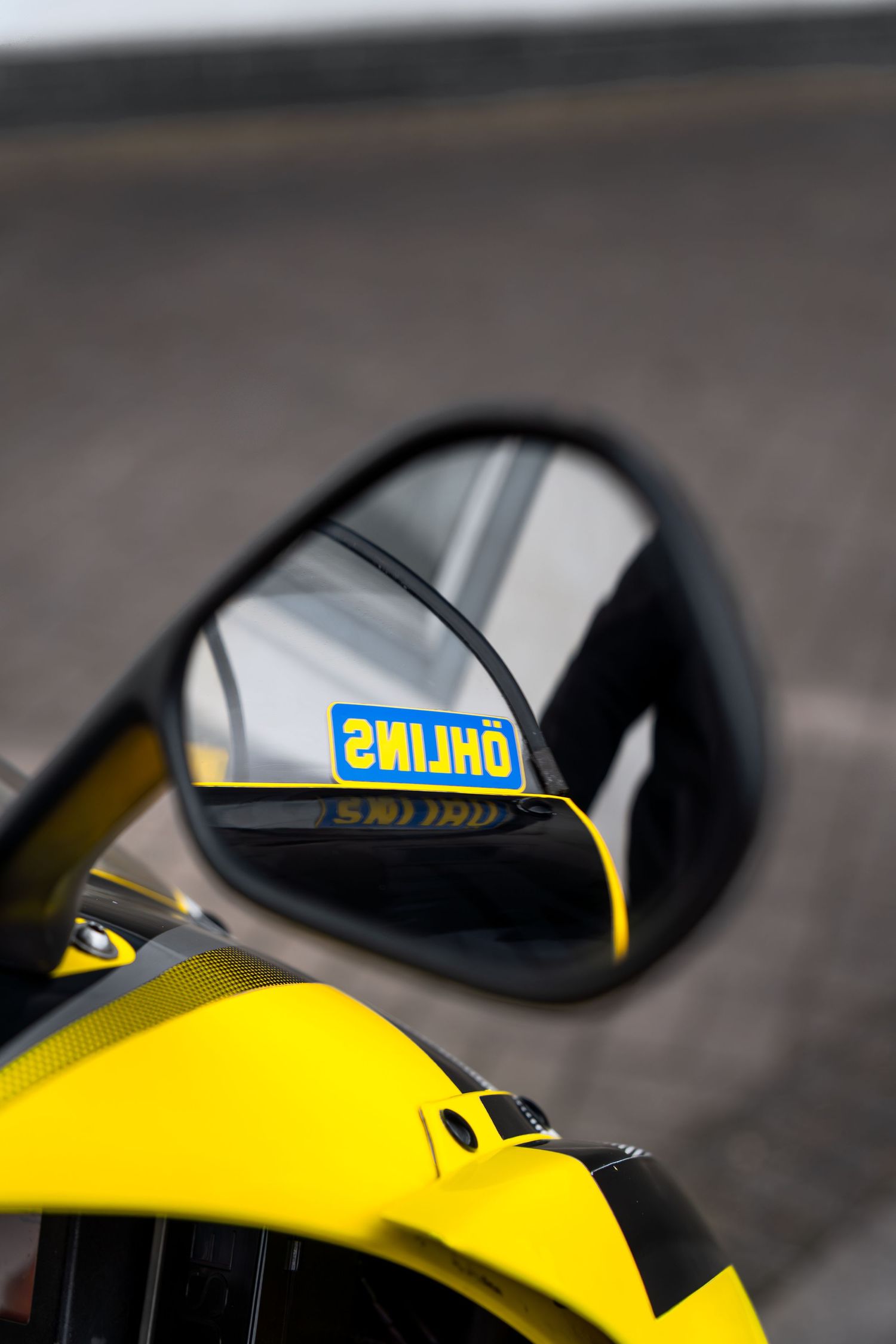 Ohlins suspension sticker reflected in the wing mirror of a yellow sport motorcycle.