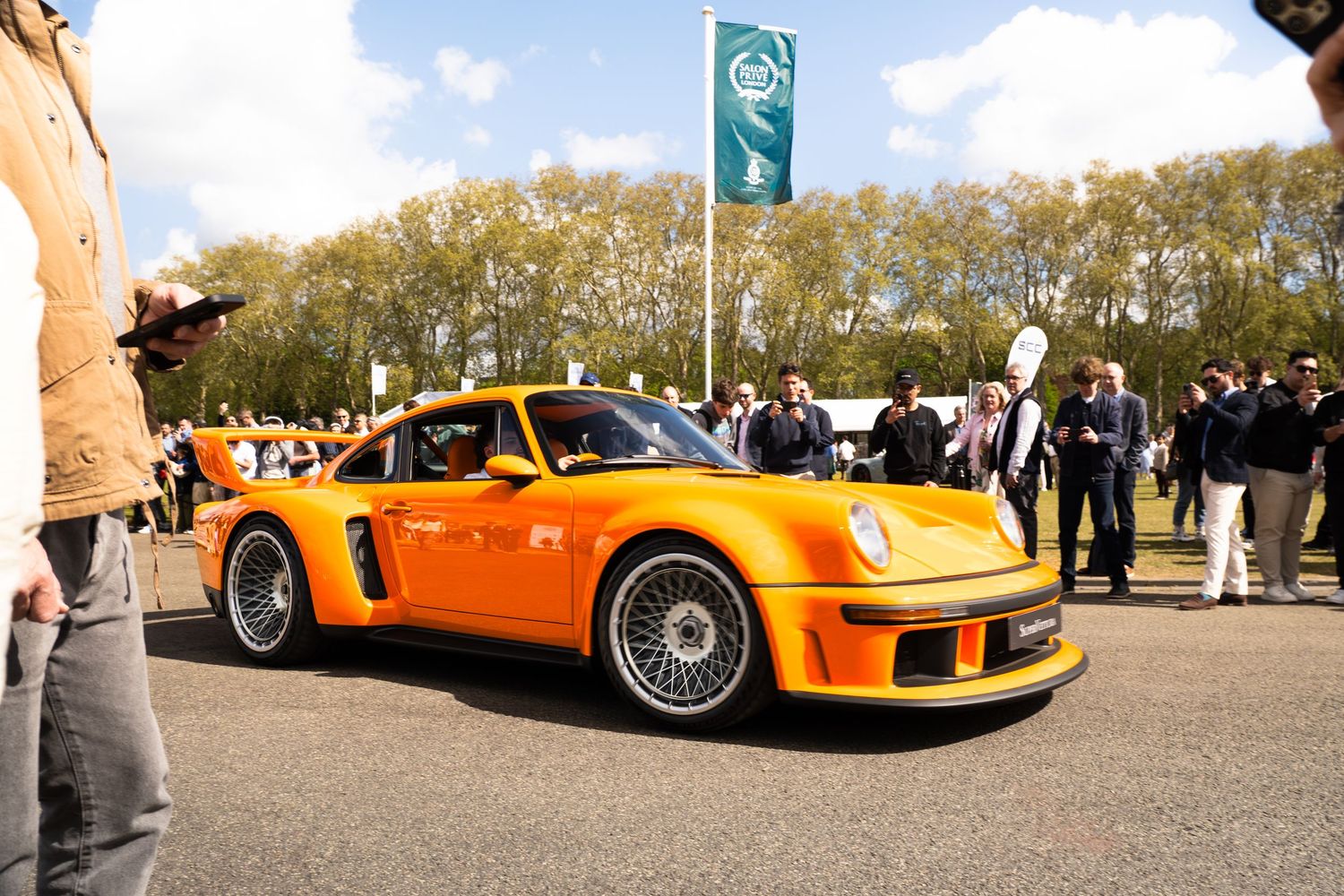 Stunning orange RWB Porsche 930 Turbo on display at an outdoor exotic car event.