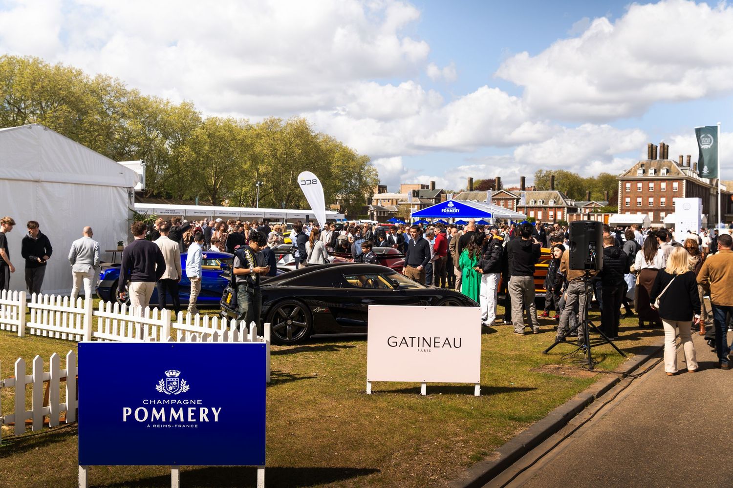 Crowds gather at the Pommery Champagne and Gatineau sponsored luxury car show on a sunny day.