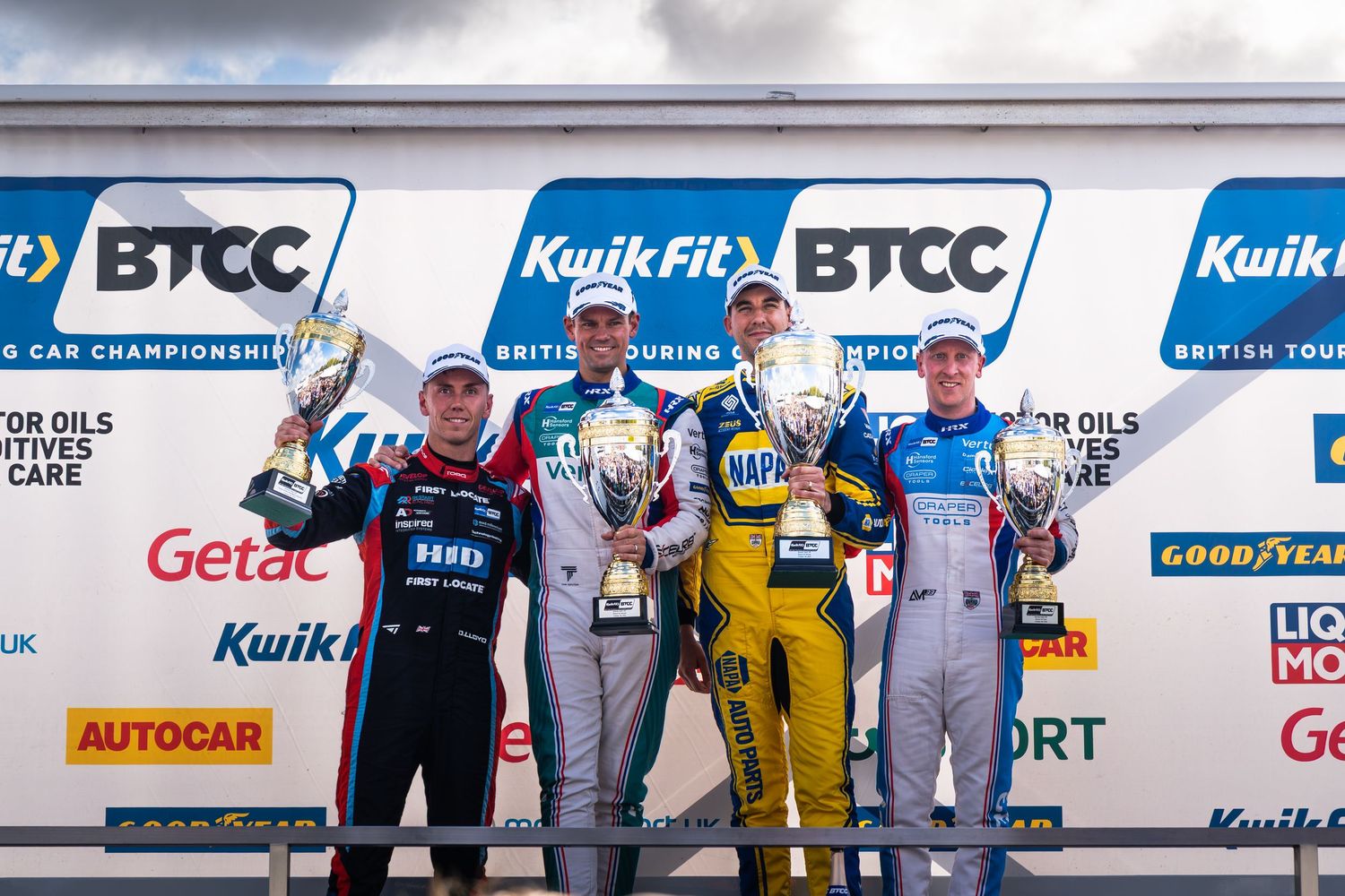 Three drivers celebrate with trophies on the KwikFit BTCC British Touring Car Championship podium.