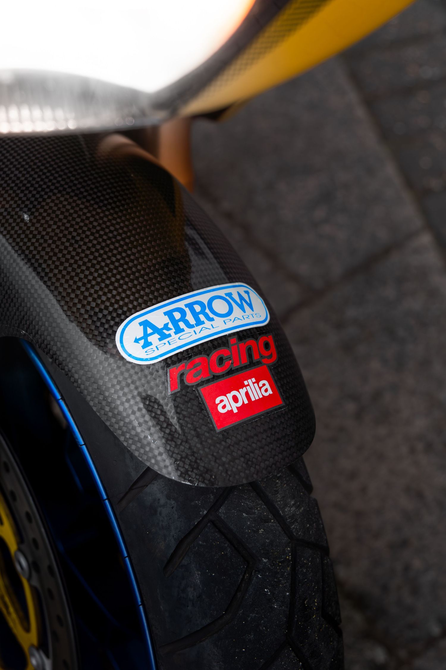 Carbon fiber front fender of Aprilia motorcycle with Arrow racing and Aprilia decals.