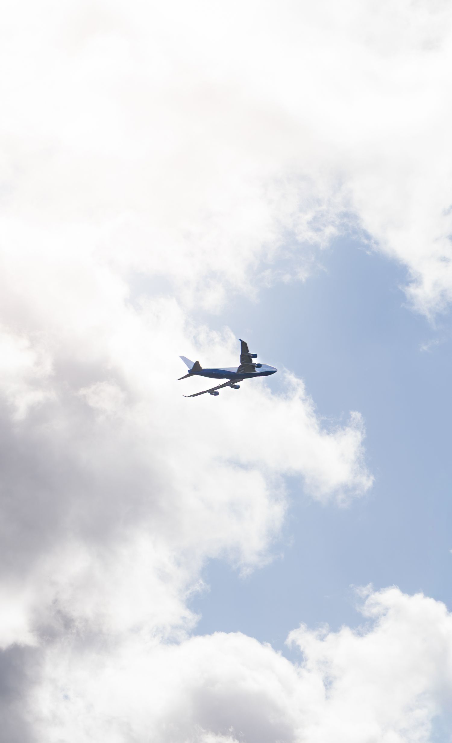 Commercial airplane flying through a partly cloudy blue sky viewed from below.