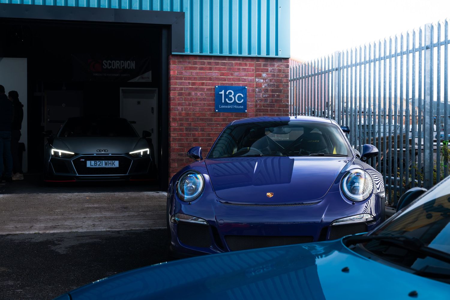 Purple Porsche 911 GT3 parked outside unit 13c with an Audi R8 visible in the garage.