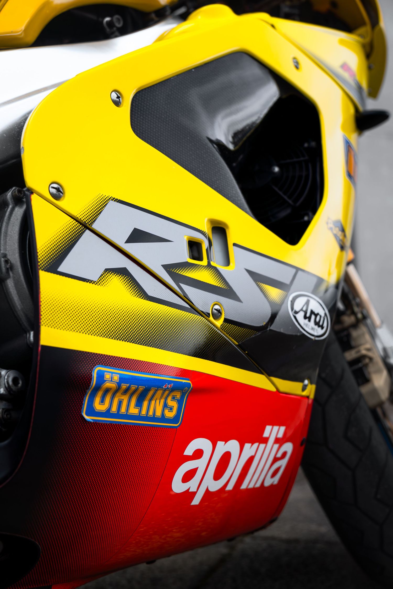 Detail shot of yellow Aprilia RS5 fairing with Ohlins and Aprilia branding stickers.
