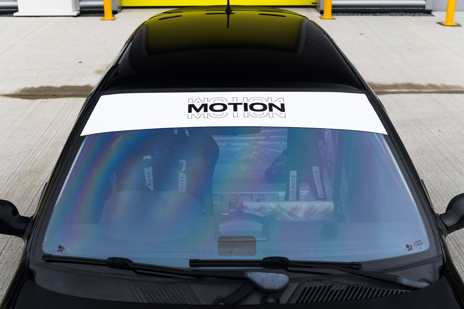 Close-up of a black car windshield featuring a white Motion banner strip across the top.