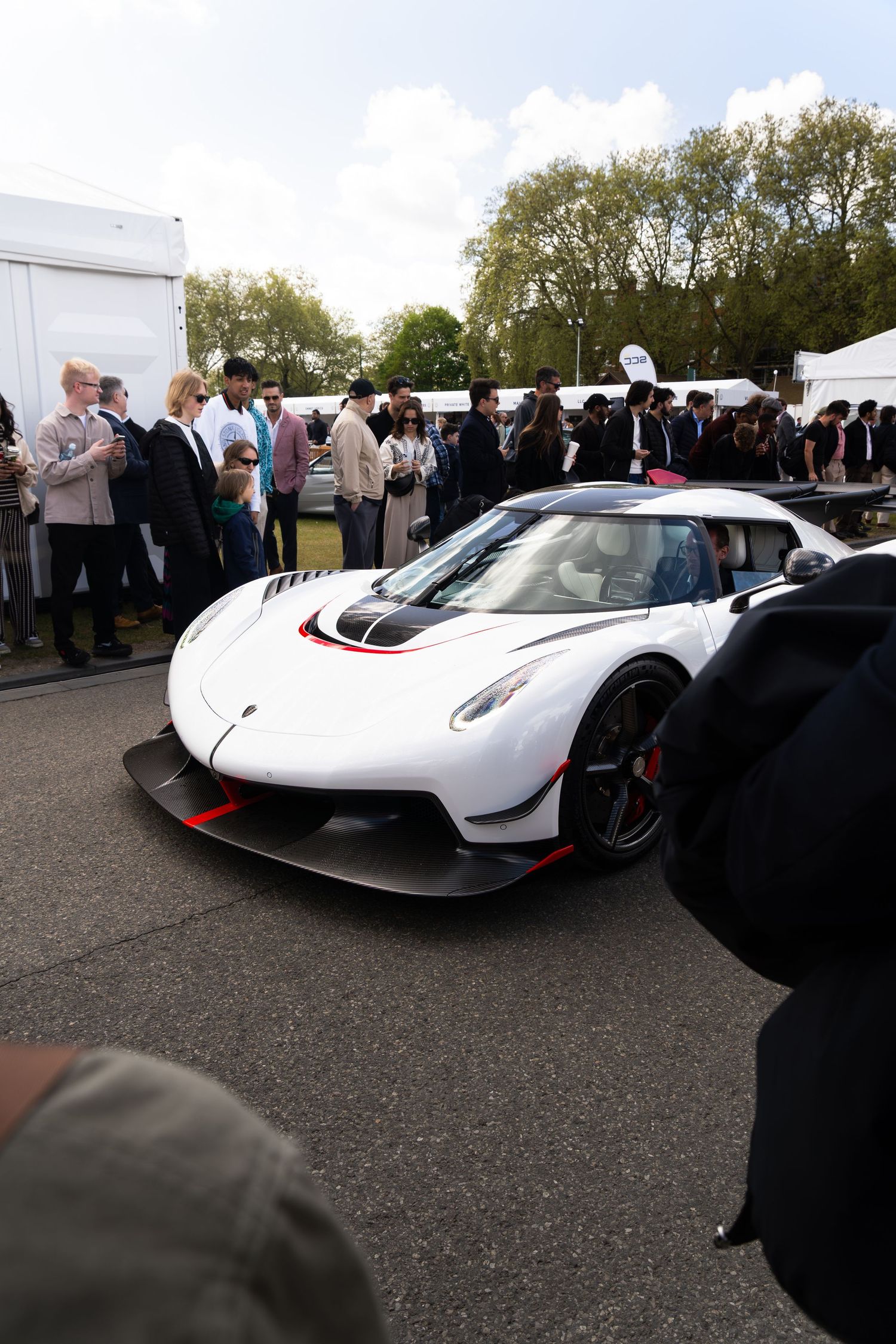 White Koenigsegg Jesko hypercar with red accents on display at an outdoor automotive event.