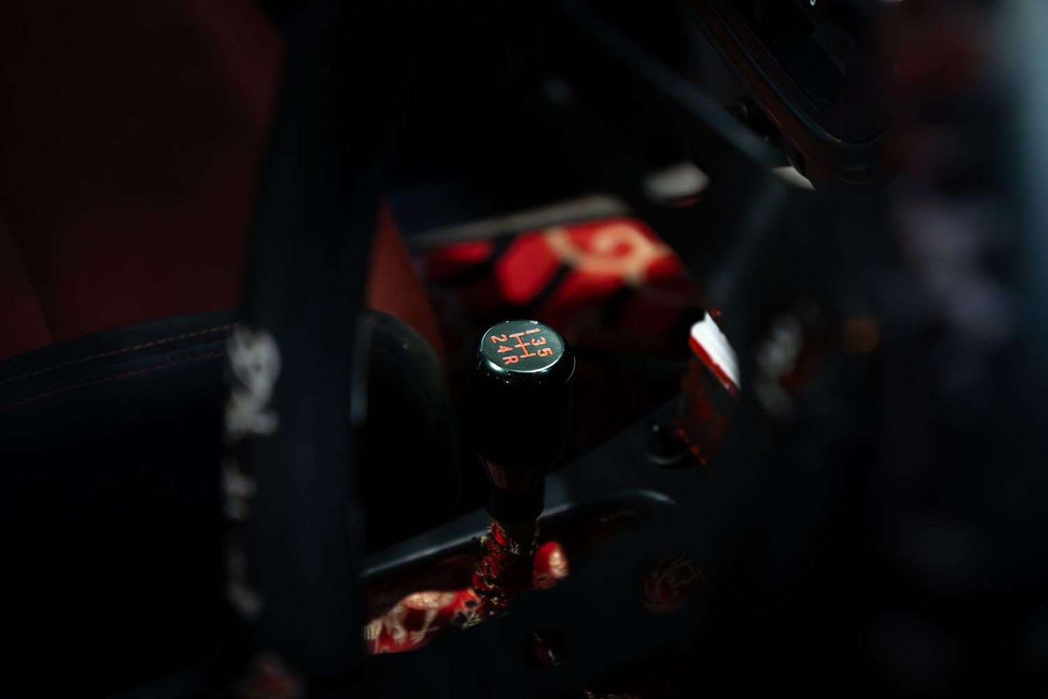 Close-up of a custom shift knob in a modified car interior with red accents and roll cage.