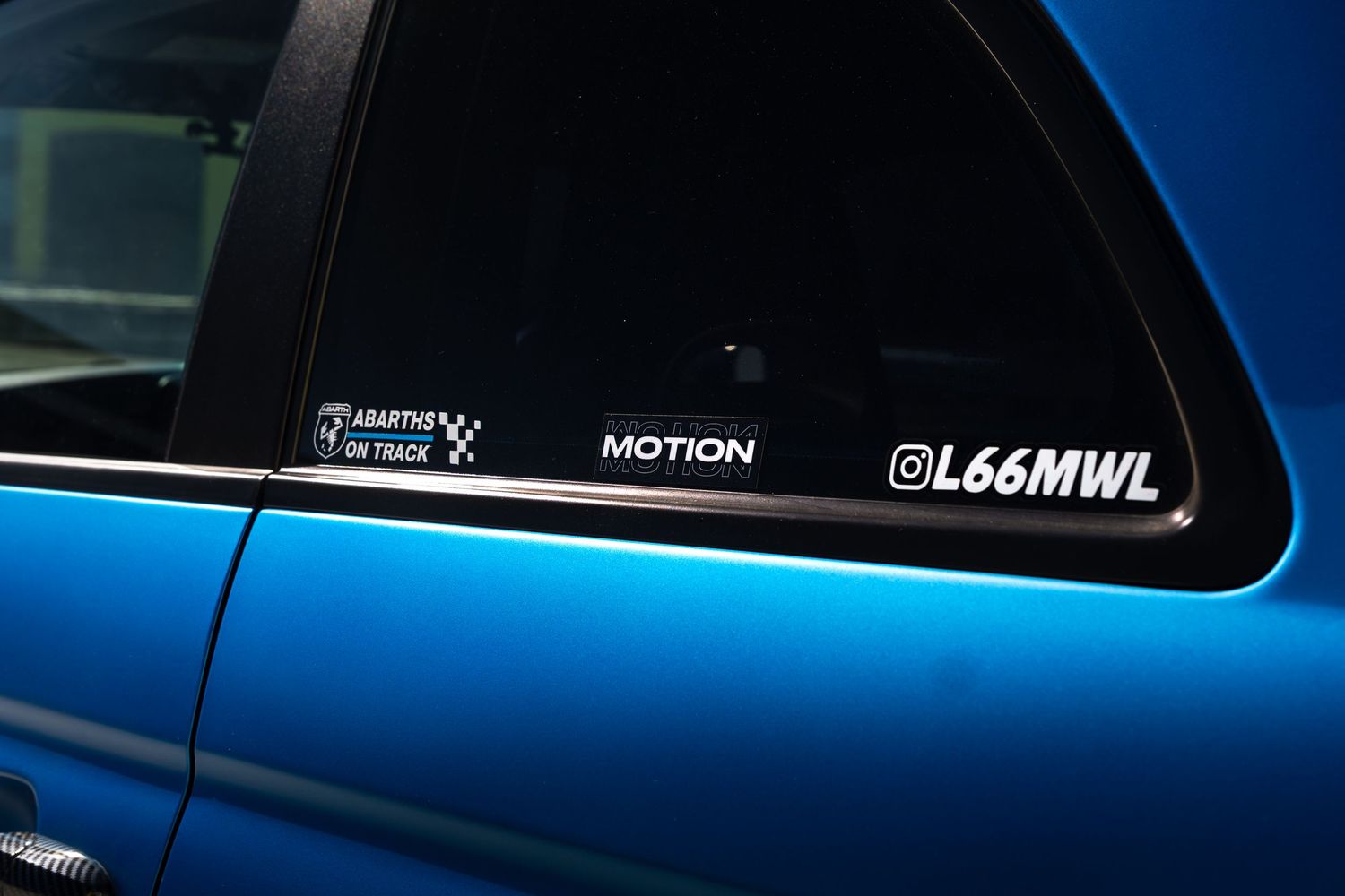 Window stickers including Abarths on Track and Motion decals on a blue Abarth 500.