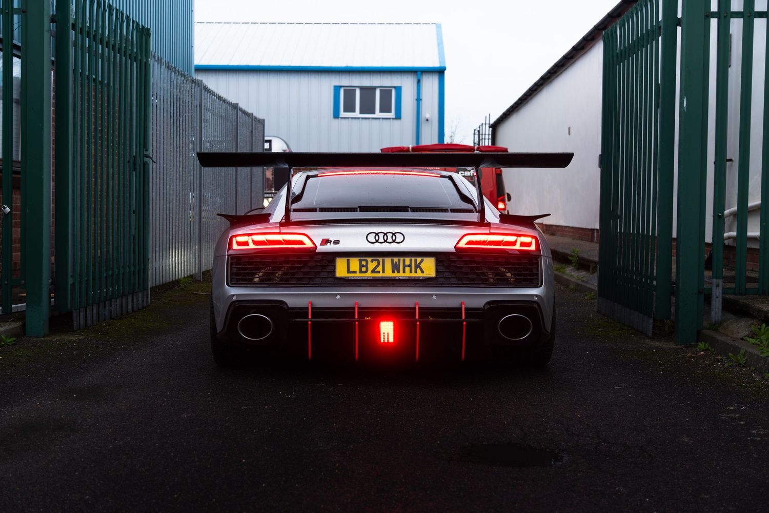 Rear view of an Audi R8 GT3 supercar with glowing red taillights.