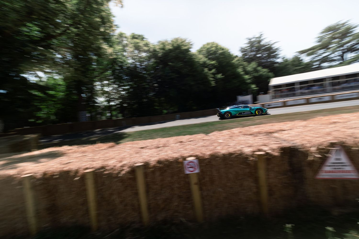 A racing car speeds past hay bales at the Goodwood Festival of Speed hillclimb event.