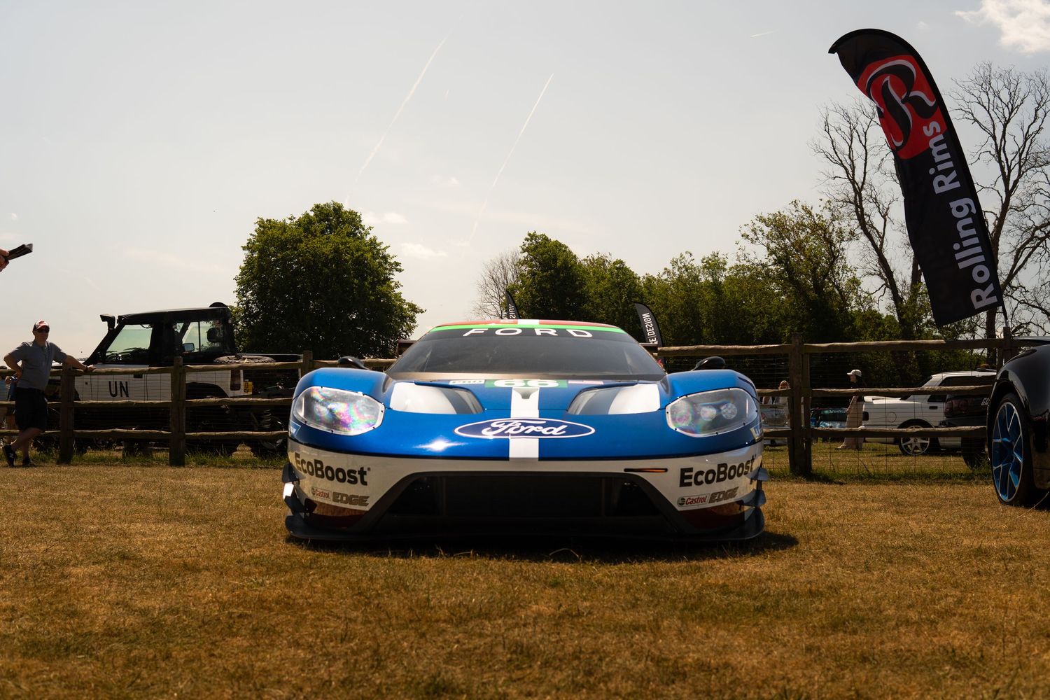 Ford GT race car in blue and white livery displayed on grass at car show.