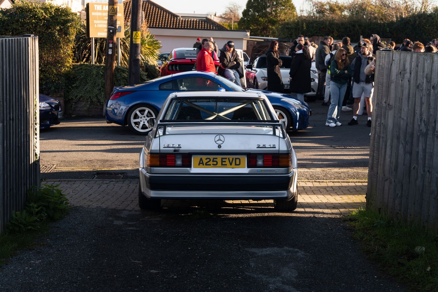 Rear view of silver Mercedes-Benz 190E with registration A25 EVD leaving a car meet.