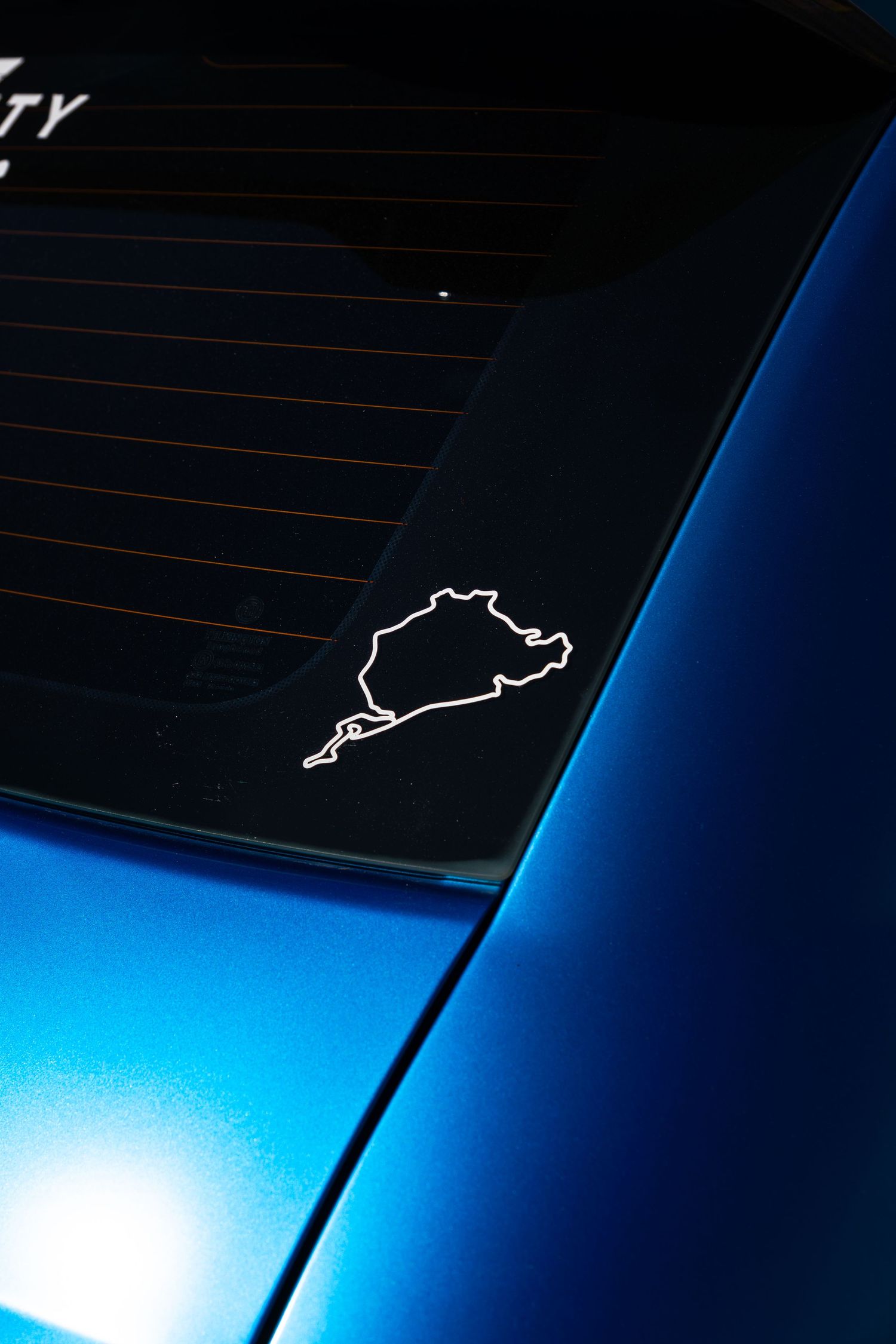 Nurburgring circuit outline sticker on the rear window of a blue Abarth 595 sports car.