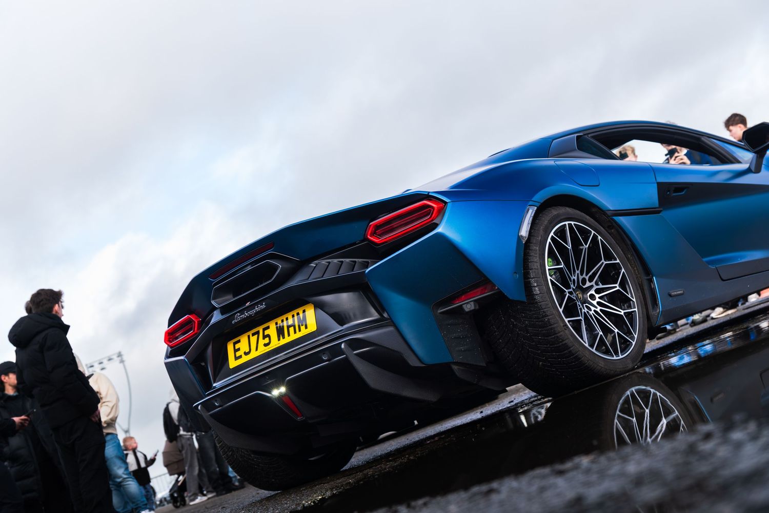 Blue McLaren supercar rear view with UK number plate EJ75WHH at a car show.
