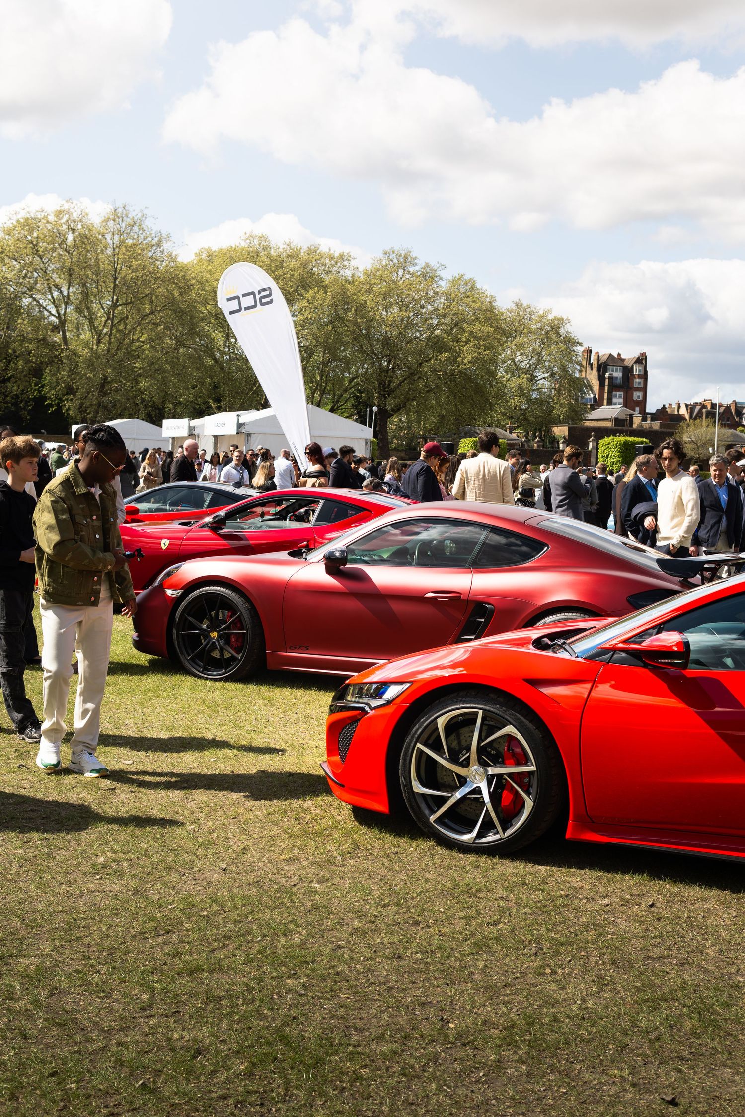 Row of red supercars including Honda NSX on display at an outdoor luxury automotive show event.