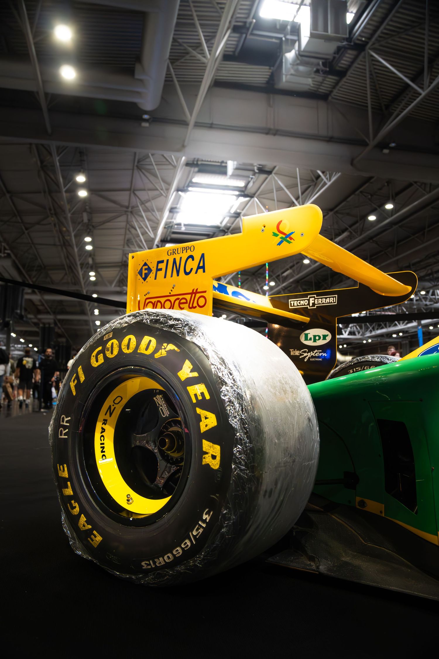 Close-up of Goodyear Eagle F1 slick tire on a Benetton Formula 1 race car at a motorsport exhibition.