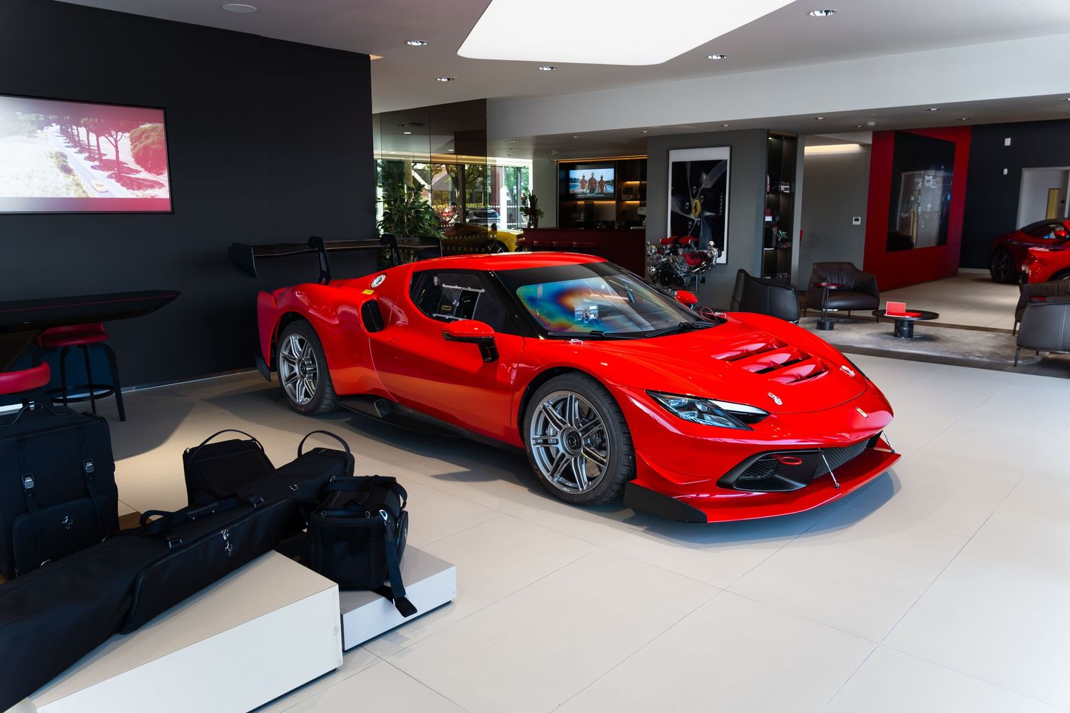 Red Ferrari supercar displayed in a luxury dealership showroom with sleek modern interior design.