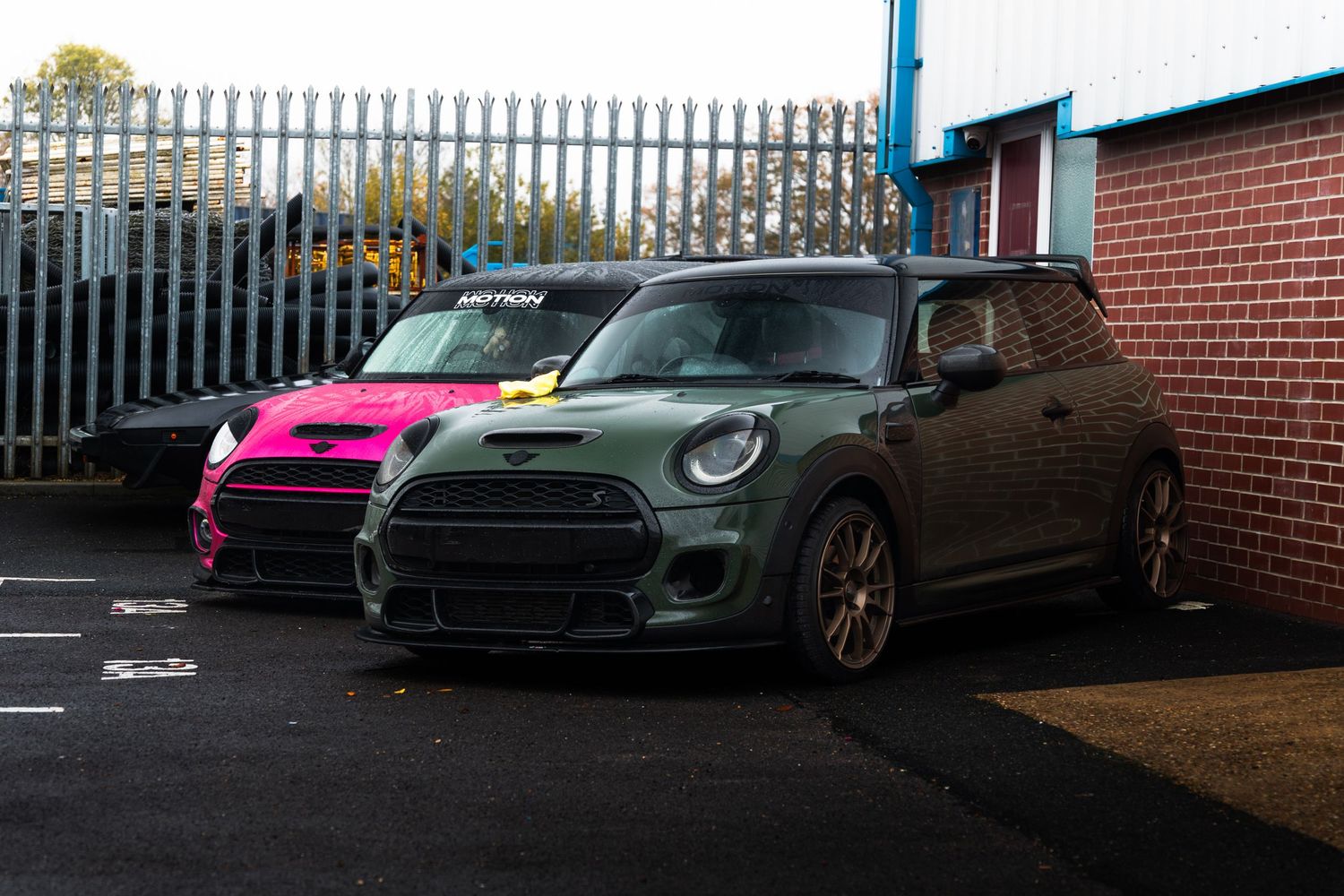 Two modified MINI Cooper S cars parked outside Motion automotive workshop.