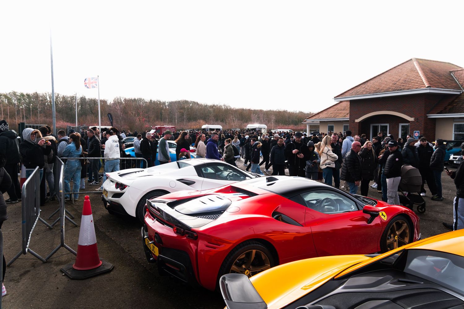 Ferrari SF90 and other supercars on display at a crowded UK car meet.