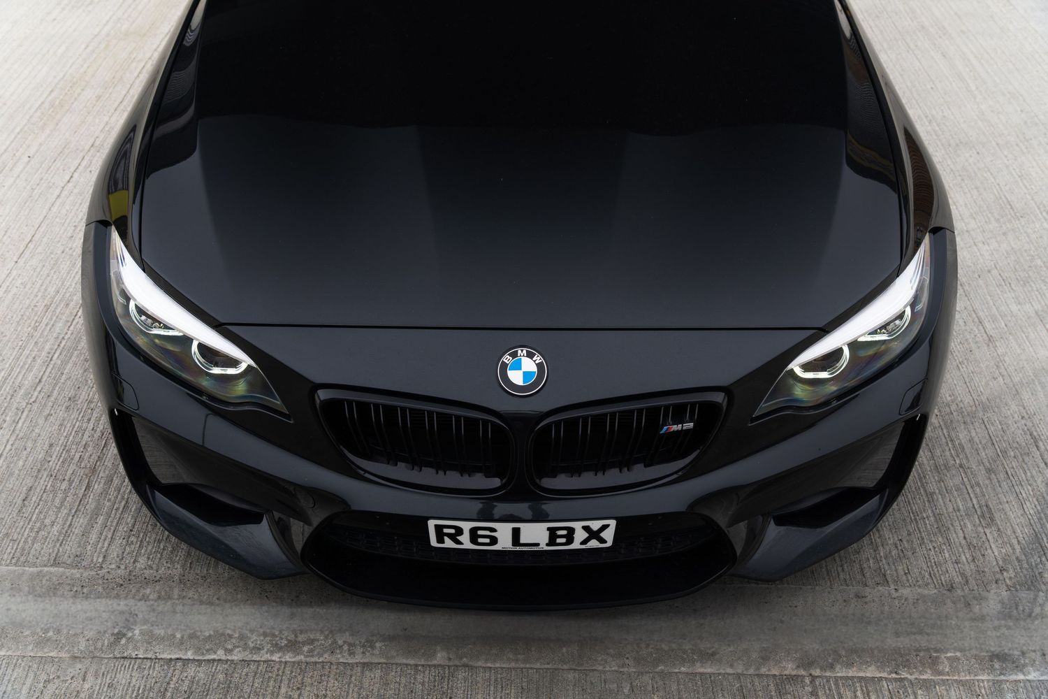 Close-up front view of a black BMW M2 coupe showing the BMW logo and headlights.