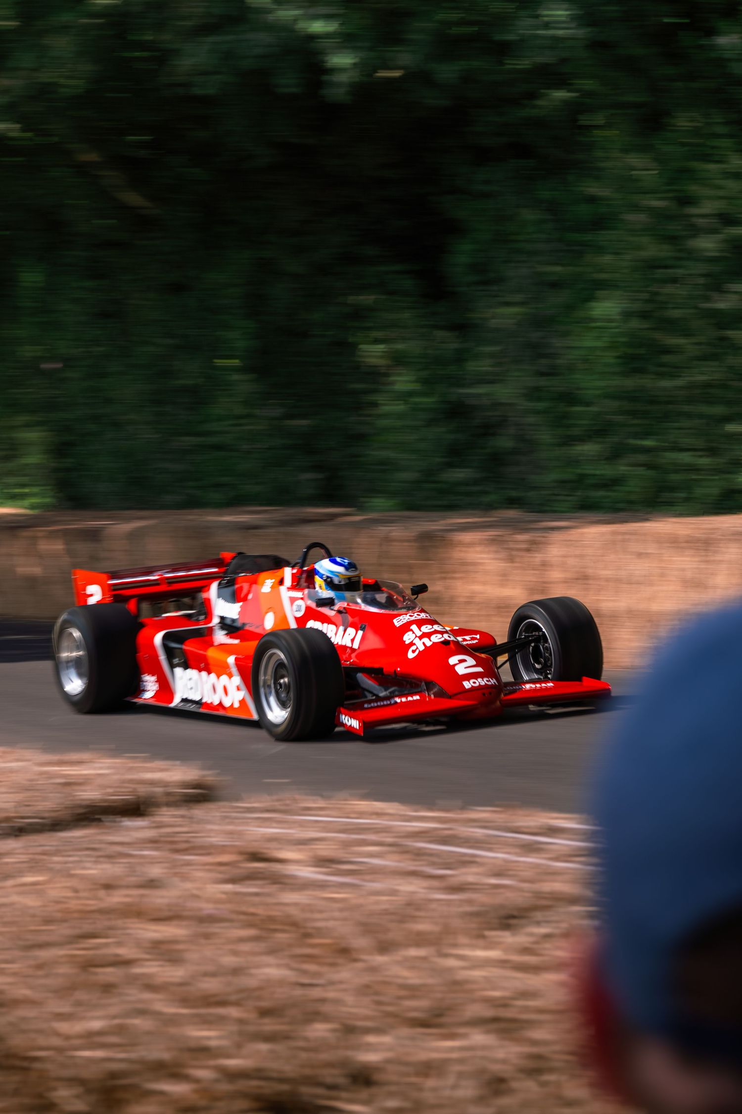 Red Formula racing car number 2 with Pennzoil sponsorship speeding on track at Goodwood Festival of Speed.