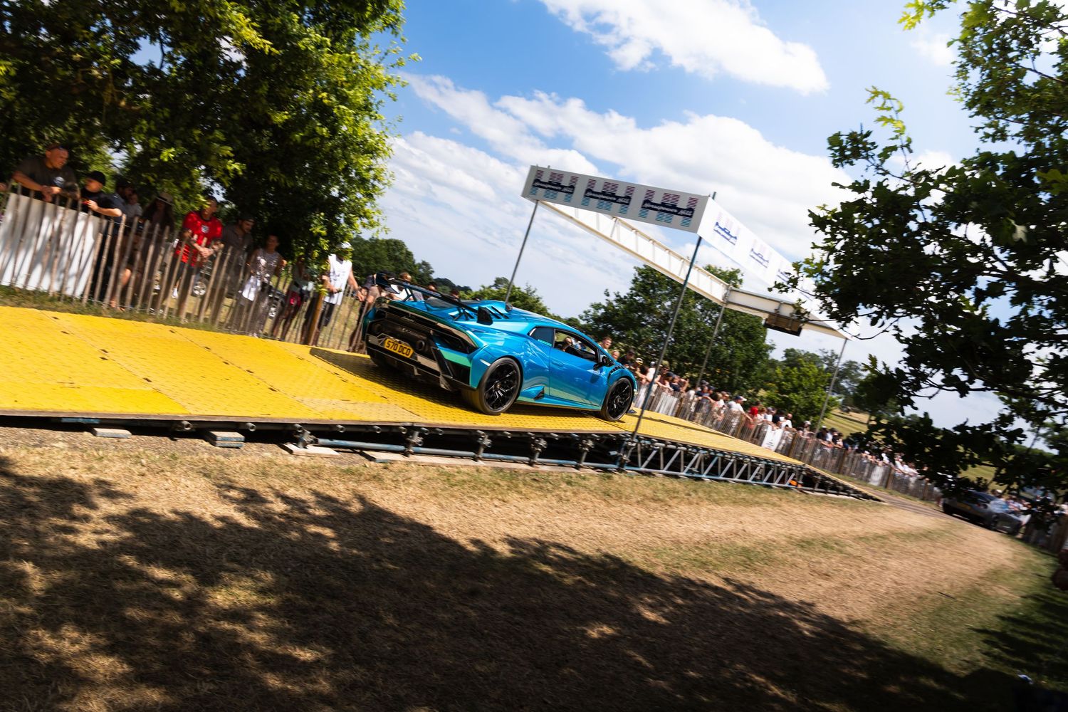 A blue Lamborghini Huracan races up a hill climb at the Goodwood Festival of Speed event.