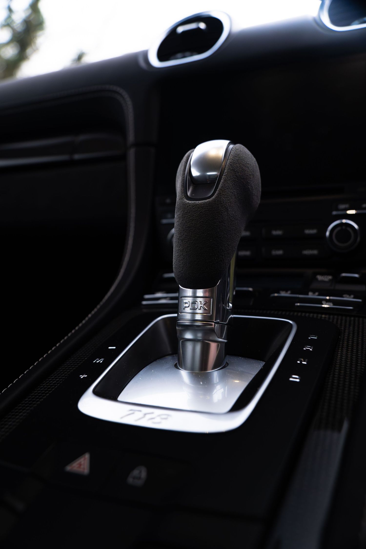 Close-up of Porsche Cayman GTS PDK gear selector shifter in dark alcantara and aluminum trim.