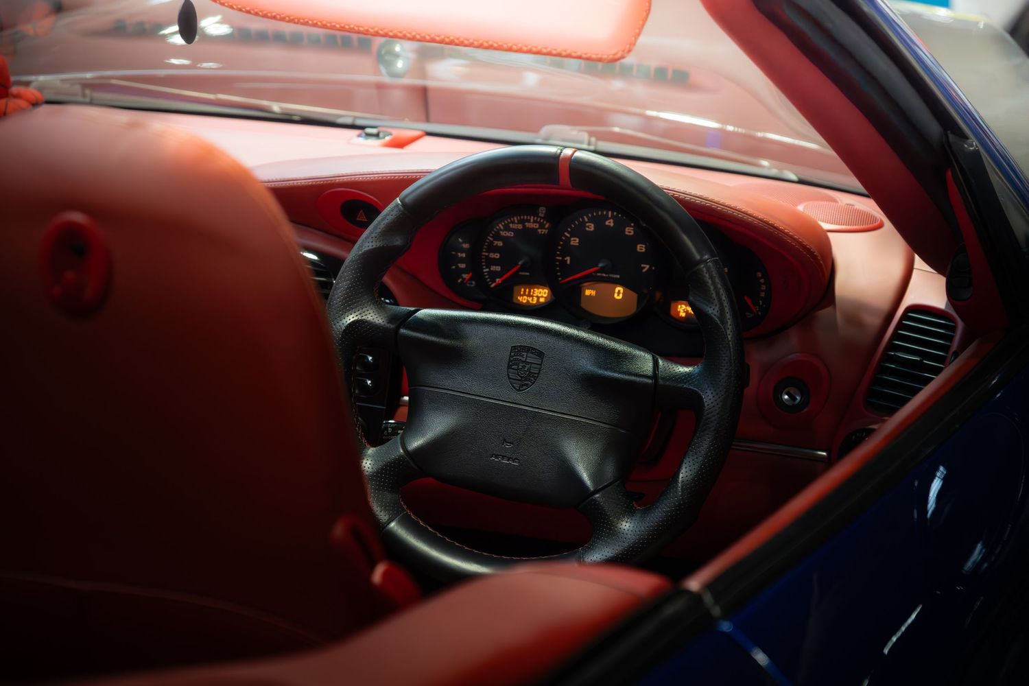 Interior of a classic Porsche featuring red leather seats, black steering wheel and dashboard gauges.