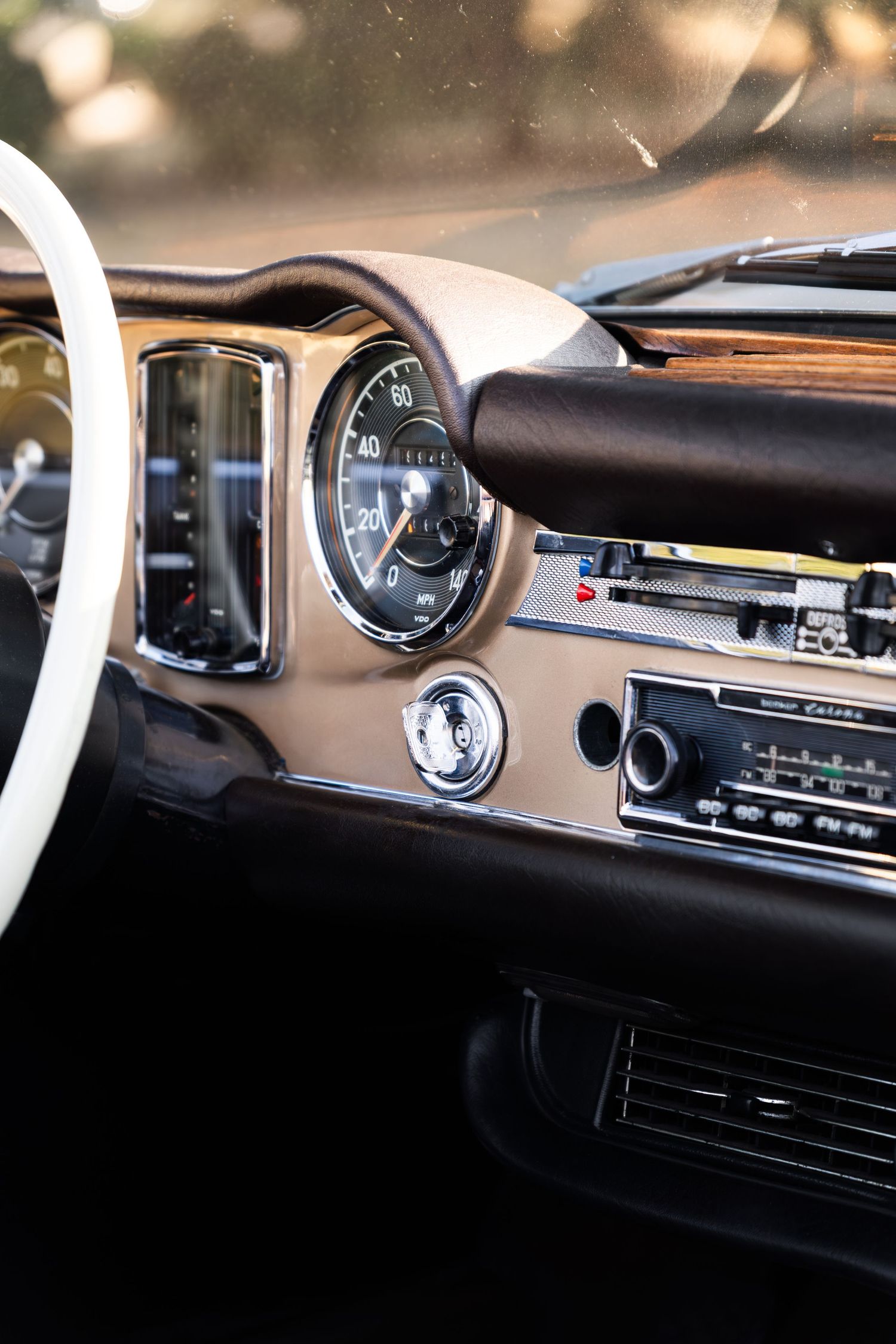 Vintage car interior with classic dashboard, analog speedometer, retro radio, and elegant beige trim detailing.