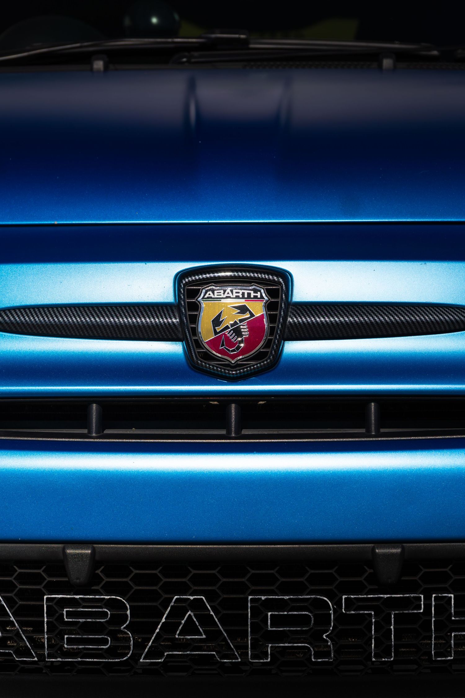 Close-up of Abarth scorpion badge on the front grille of a blue Abarth 500.