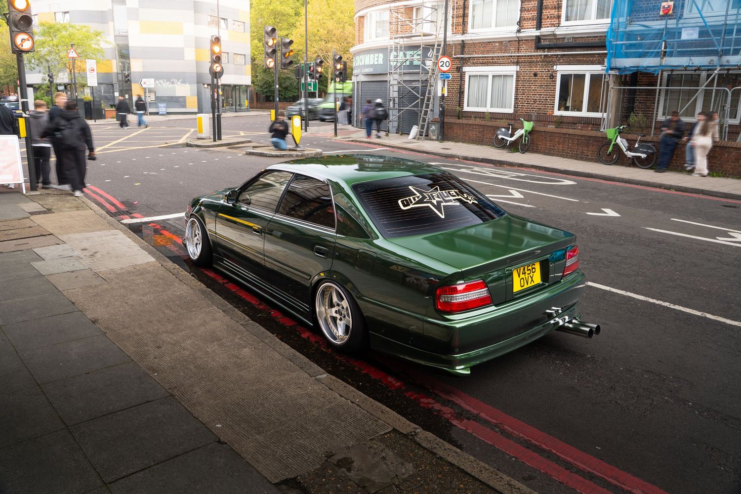 Slammed green Mercedes W124 with wide body kit parked on a London street.