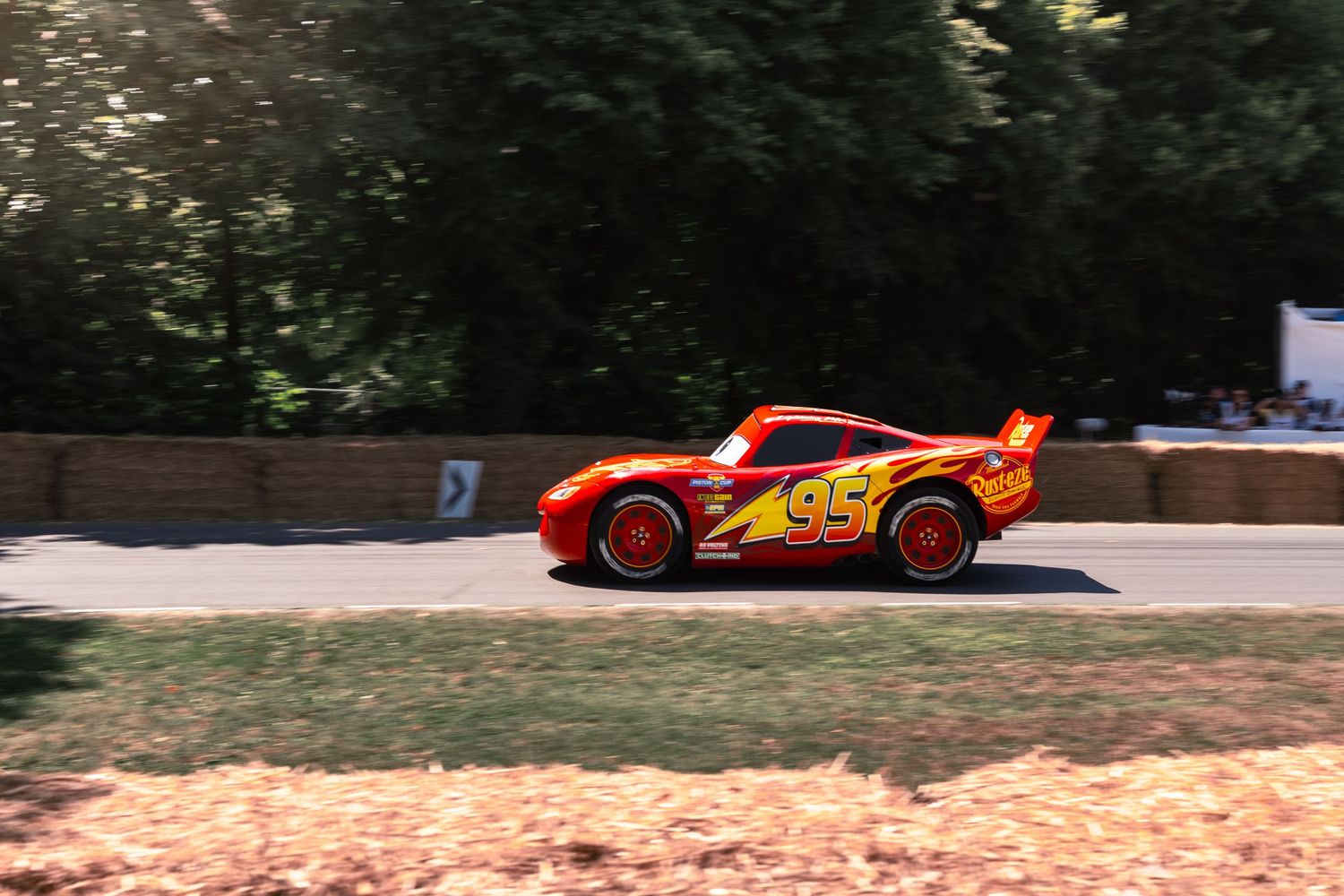 Lightning McQueen Cars movie replica race car number 95 driving on a track surrounded by trees.
