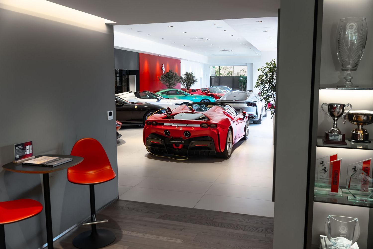 Luxury Ferrari dealership showroom featuring a red sports car on display with trophies and modern interior design.