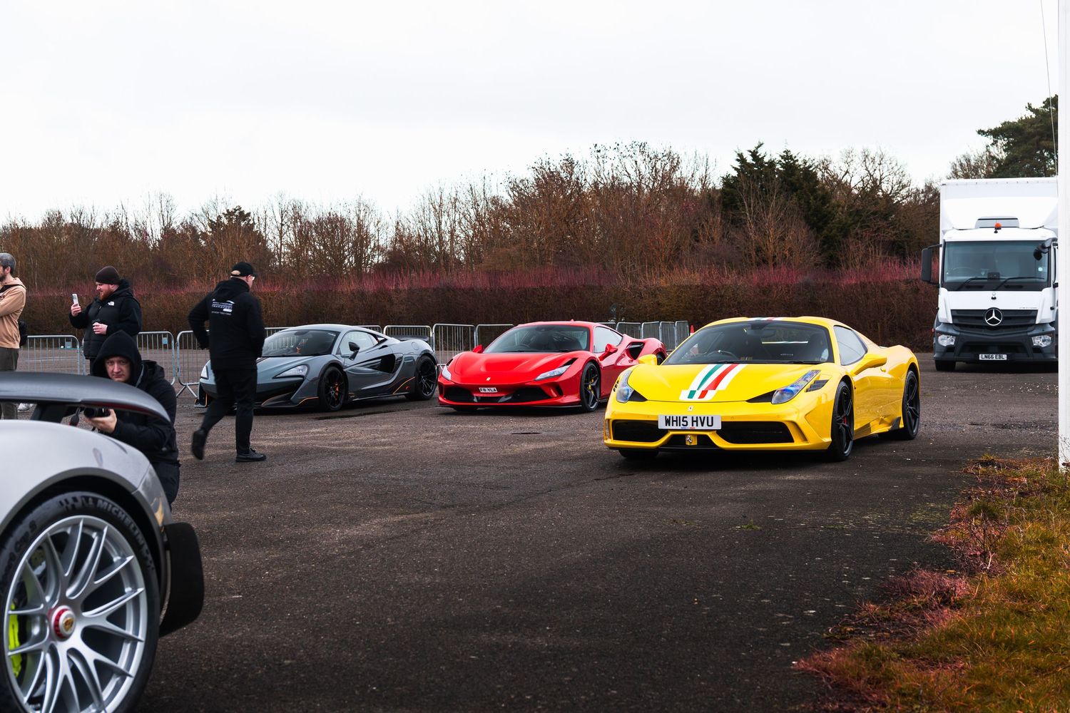 Yellow Ferrari 458 Speciale leads lineup of exotic supercars including McLaren and red Ferrari at UK track day.