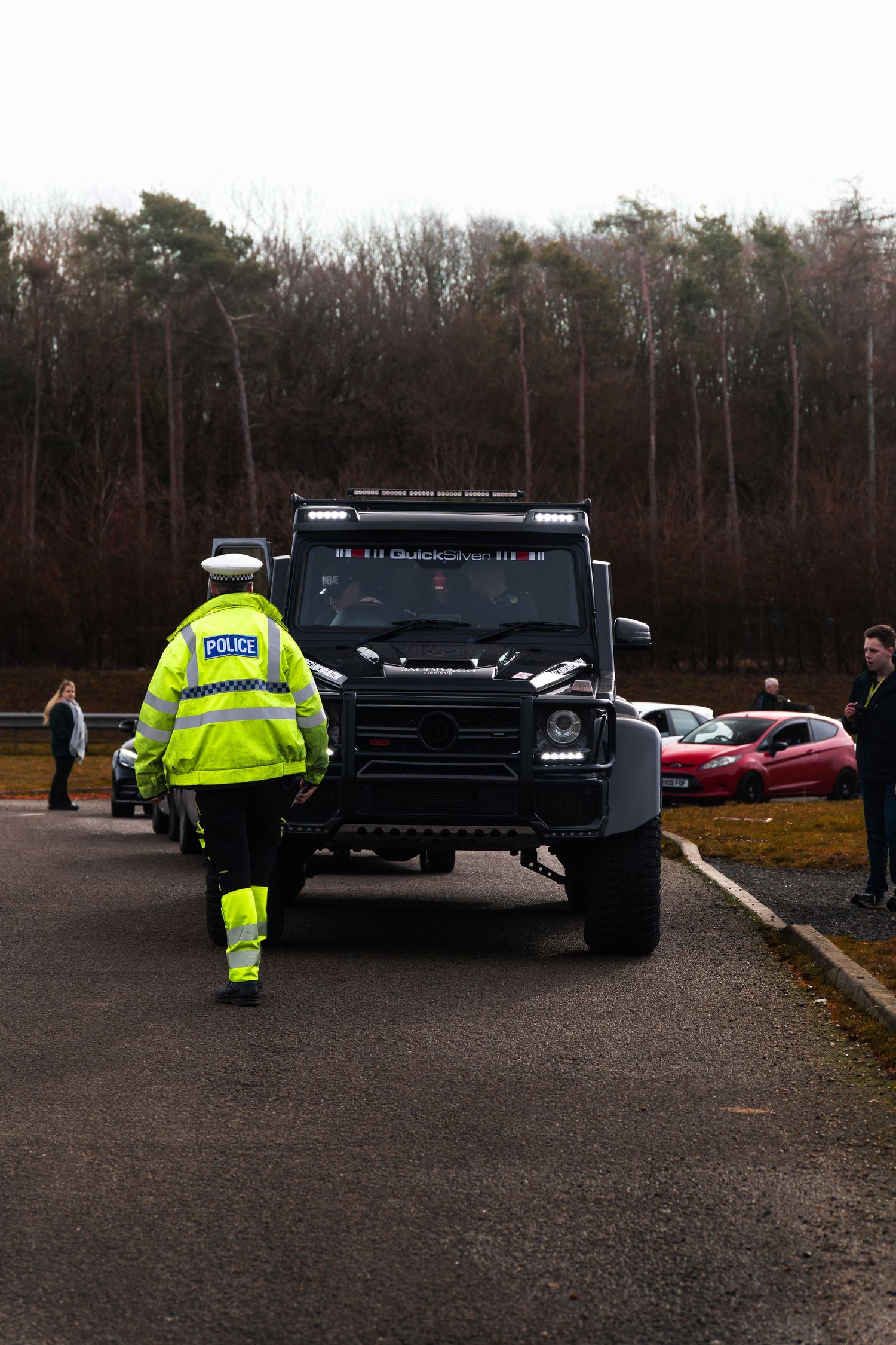 UK police officer directing a modified Mercedes G-Wagen at a car meet.